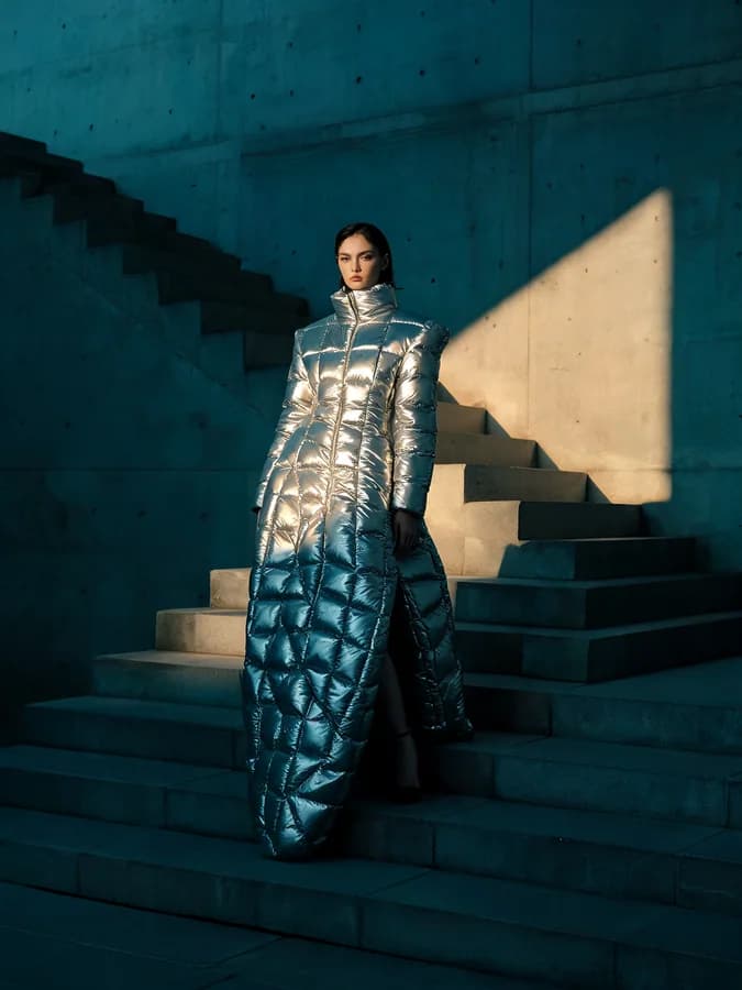 A fashion editorial generated with Seedream 5 — a model in a quilted silver puffer dress on a brutalist concrete staircase, cut by a single beam of sunlight.